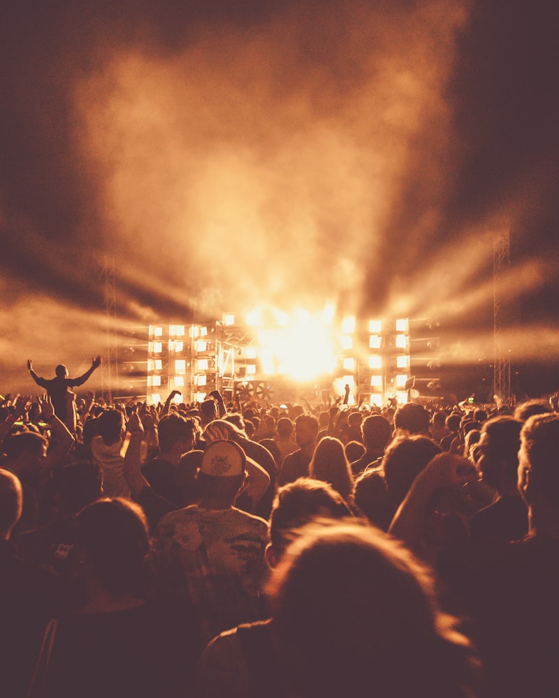Festival stage lit by a burst of white light over a packed crowd