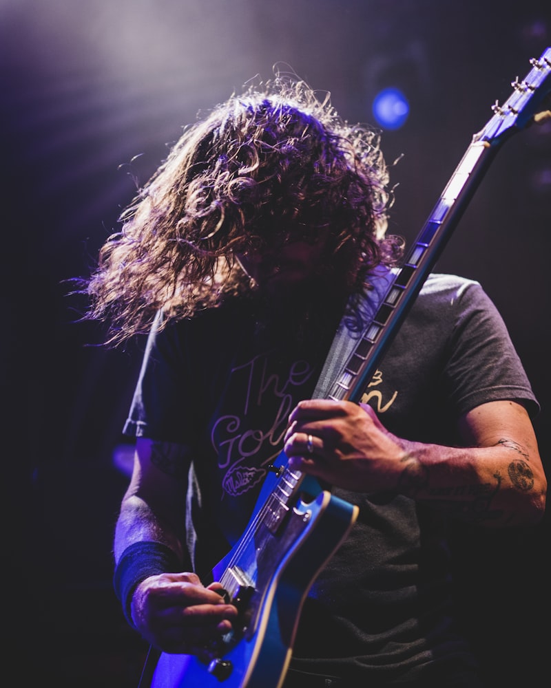Guitarist mid-riff under a purple spotlight on stage