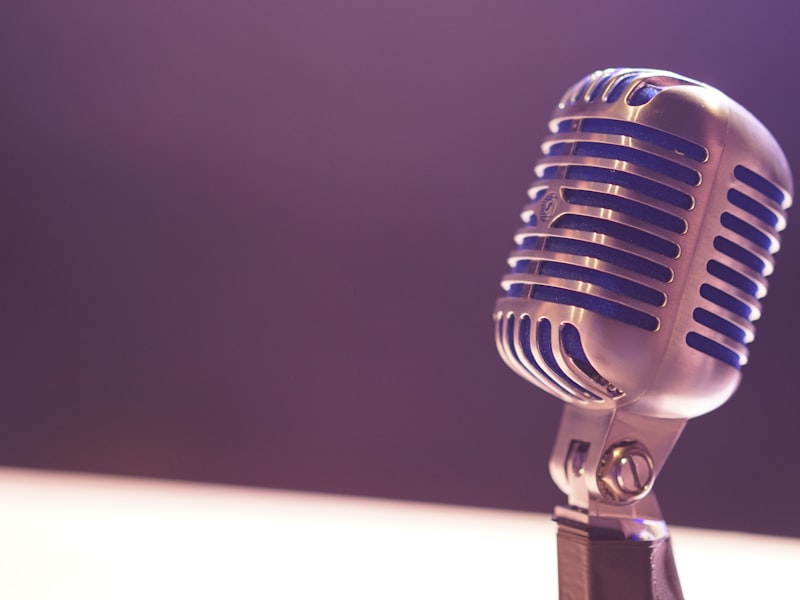 Vintage chrome stage microphone glowing under violet light