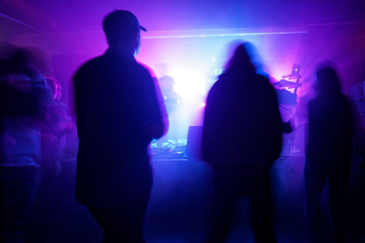 Crowd silhouettes in purple haze in front of the stage