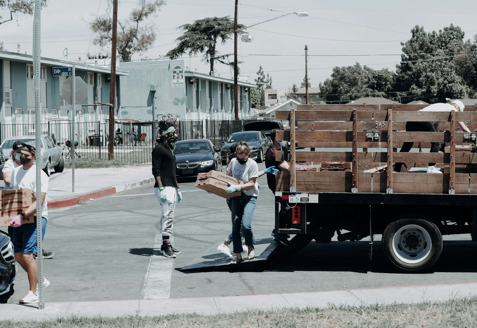 Volunteers in masks unloading boxes of fresh food from a truck at a neighborhood distribution day