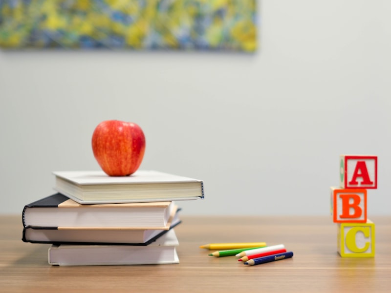 Books, an apple, colored pencils and alphabet blocks on a learning table