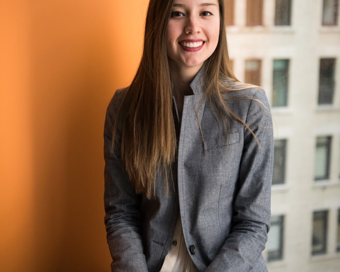 Marisol, a young woman smiling brightly against a warm orange wall