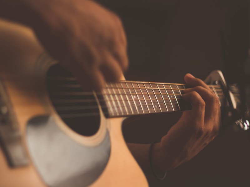 Hands playing an acoustic guitar in warm light