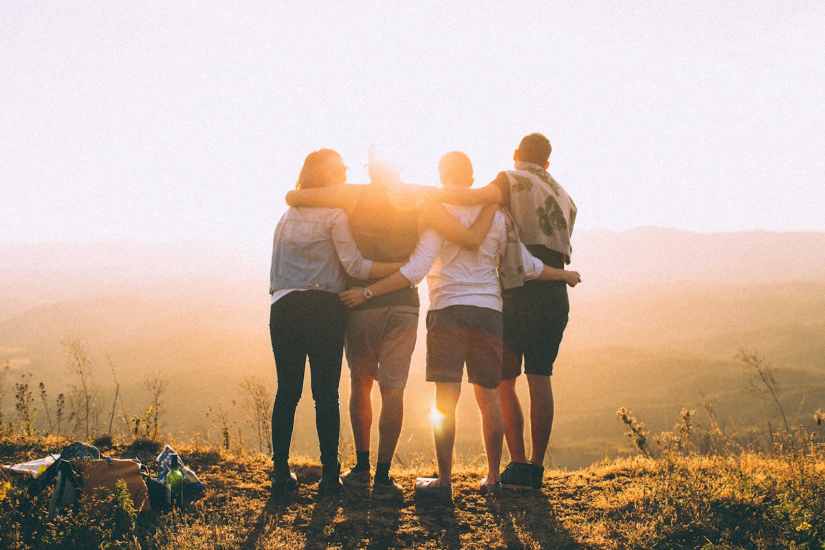 Friends standing together arm in arm at golden hour