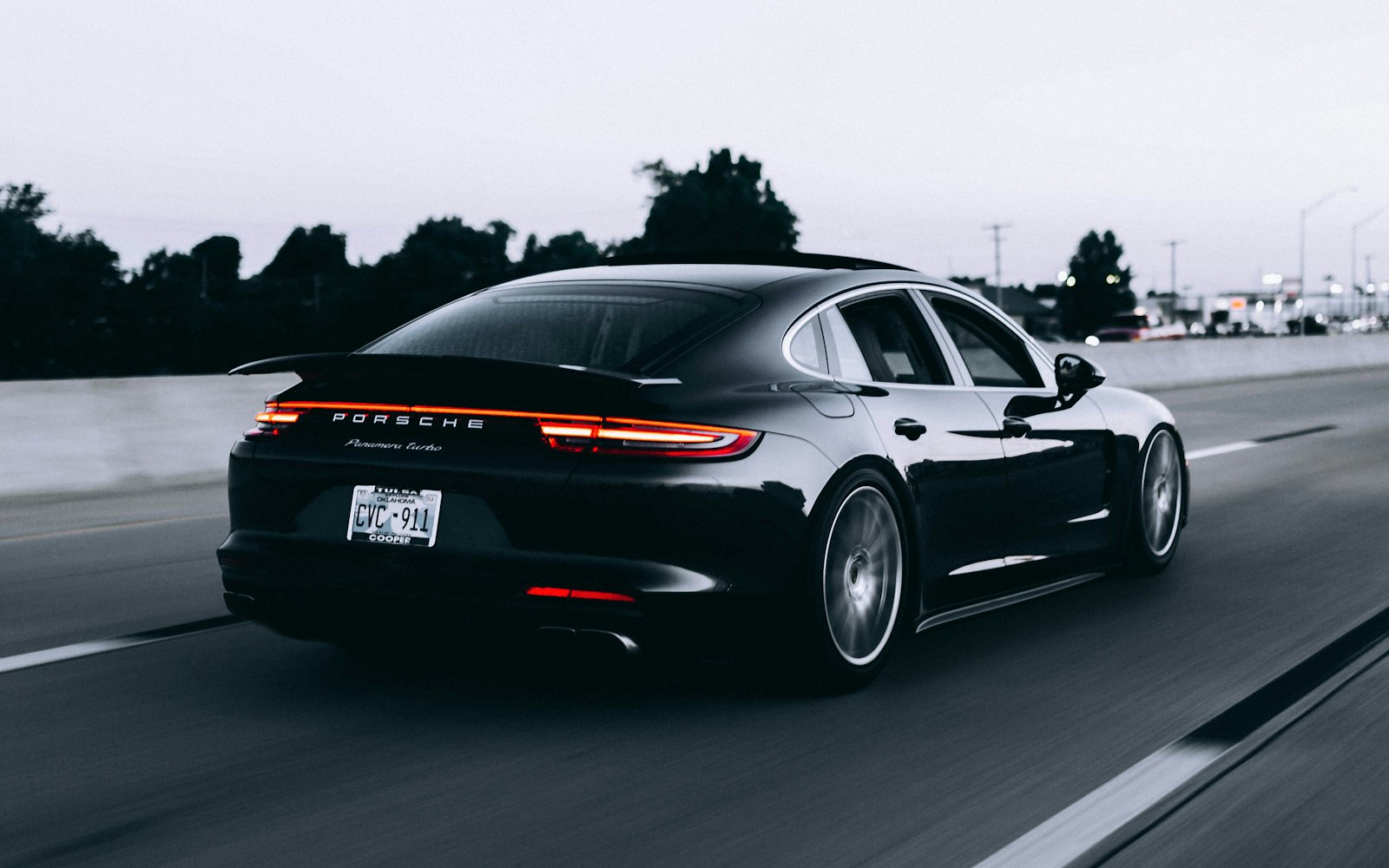 A sleek black performance sedan driving on an open highway at dusk