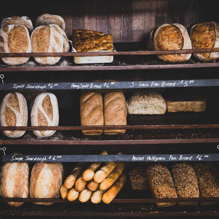 Wooden shelves of artisan loaves with handwritten chalkboard price labels