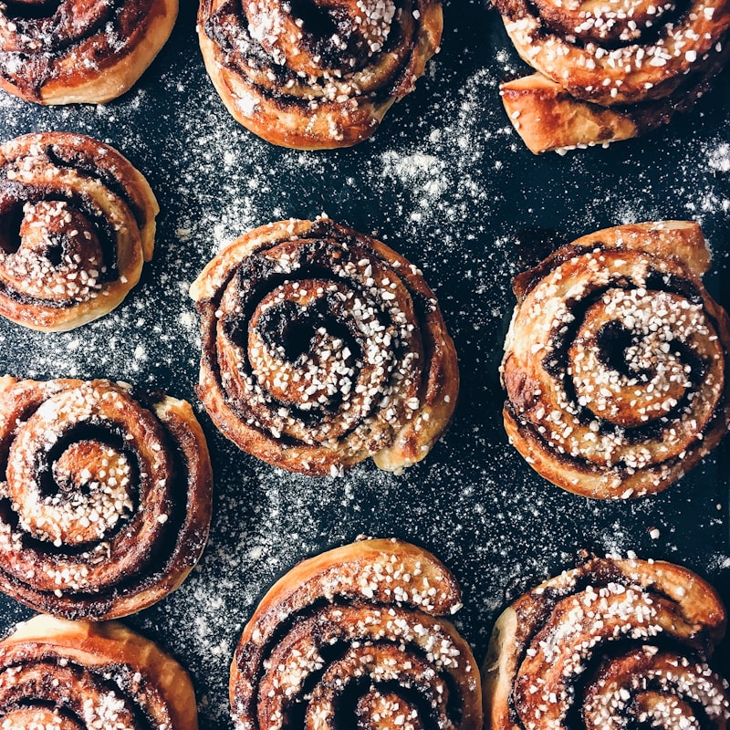 Cinnamon rolls dusted with sugar on a dark tray