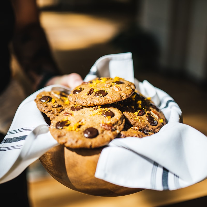Basket of warm chocolate chunk cookies wrapped in a tea towel