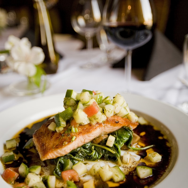 Pan-seared salmon plated over greens with a balsamic reduction and red wine.