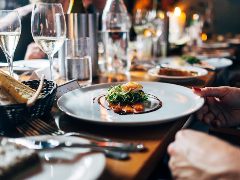 A plated fine-dining course set at a candlelit corporate dinner with wine glasses.