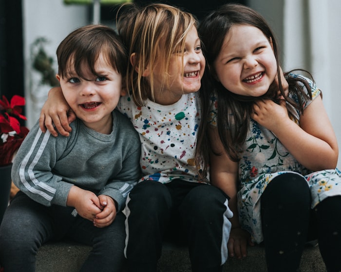 Three preschool friends laughing and hugging together