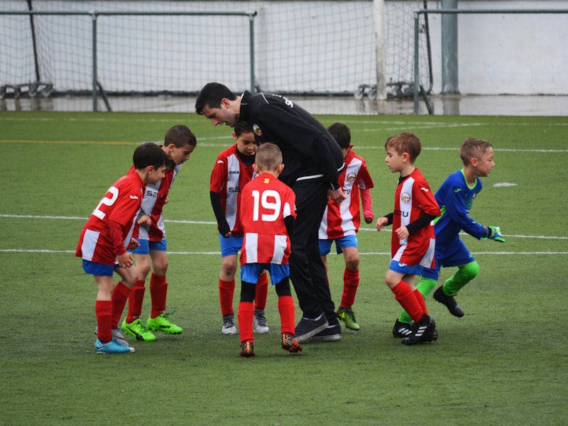 Young academy players in a huddle with their coach on the training pitch