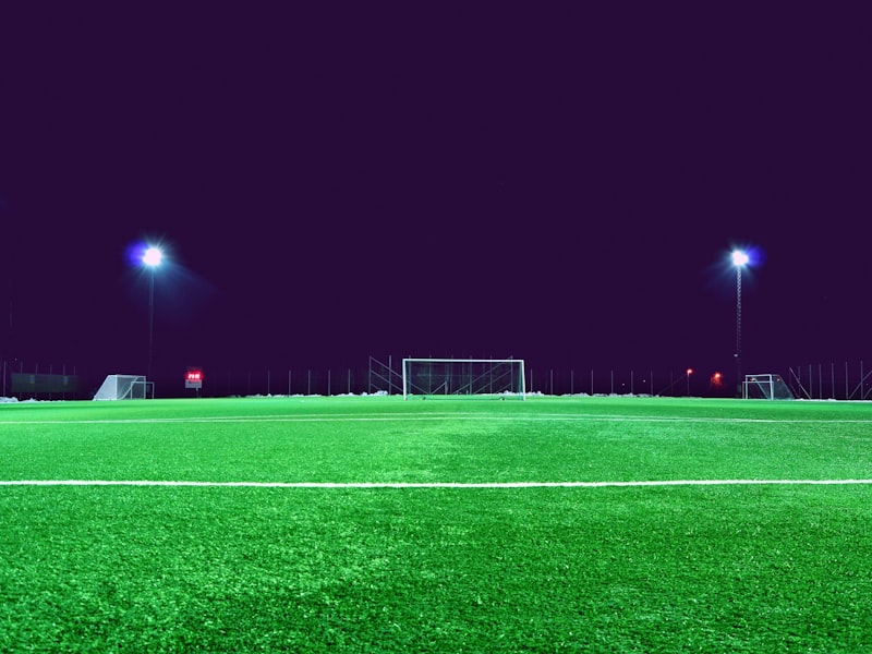 A floodlit all-weather football pitch at dusk with goals in place