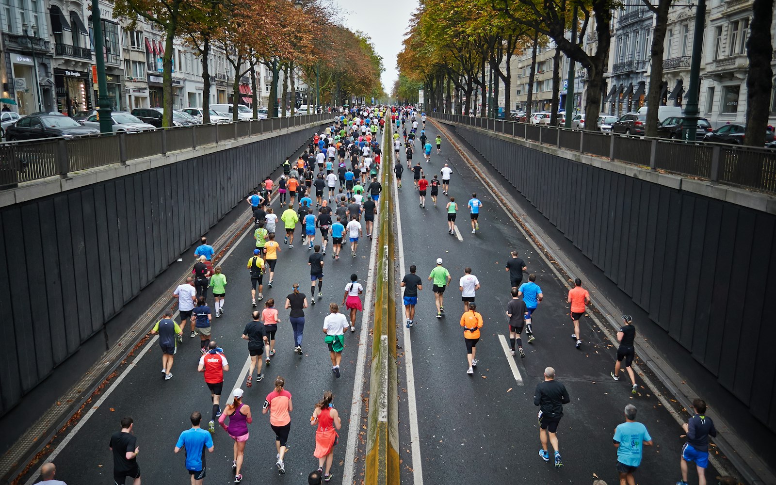 Thousands of runners filling a tree-lined city avenue during the Riverside Marathon