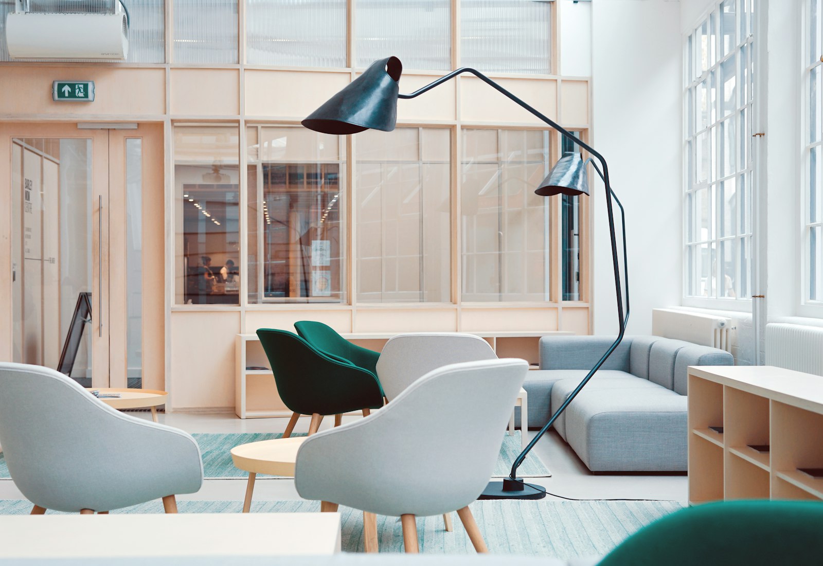 Sunlit lounge at The Annex with soft armchairs, a sofa and a sculptural floor lamp by a wall of windows