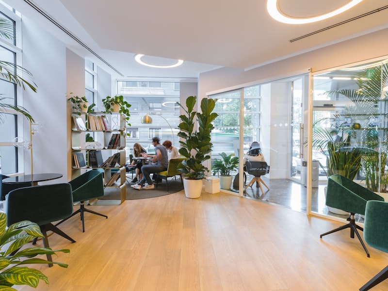 Bright, plant-filled studio with green velvet chairs where members work by the windows