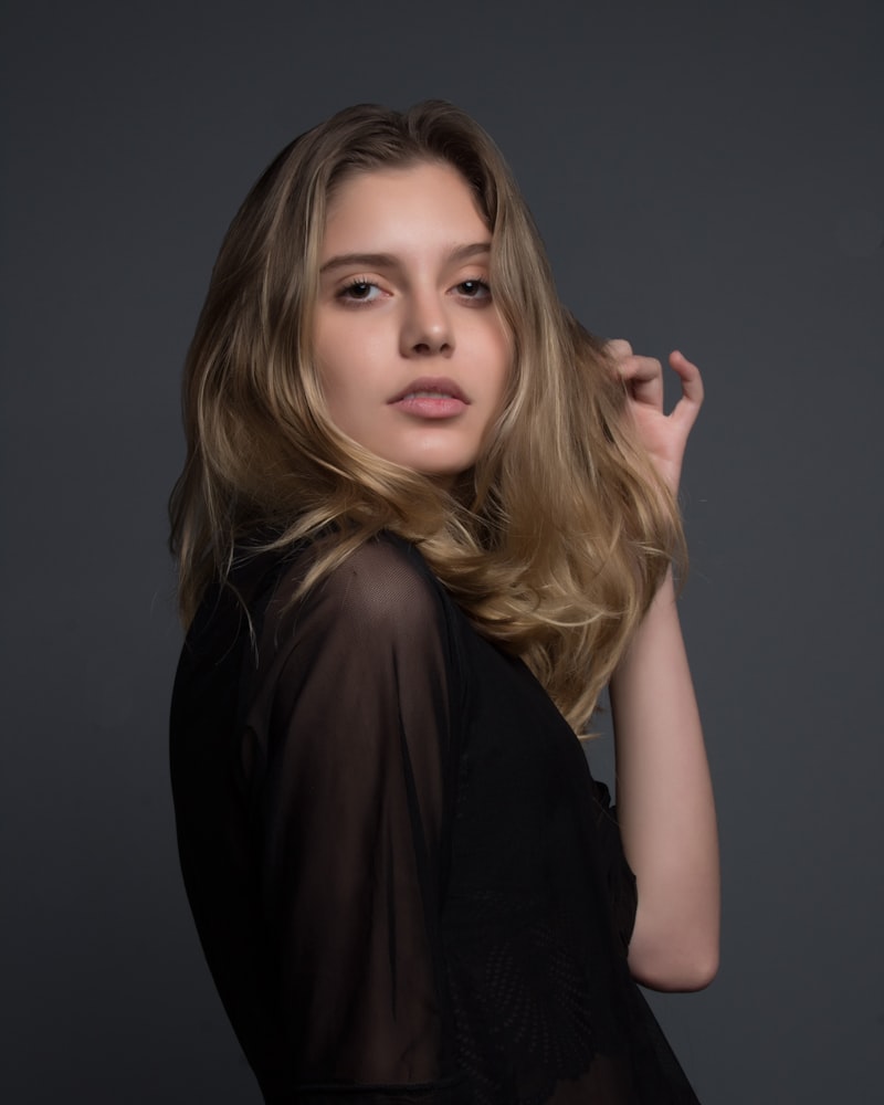 Editorial portrait of a model in a sheer charcoal top, soft studio light