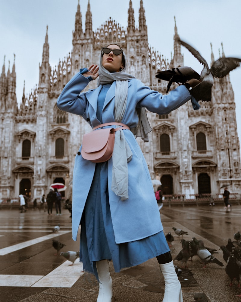 Model twirling in a cobalt blue coat on a European city square
