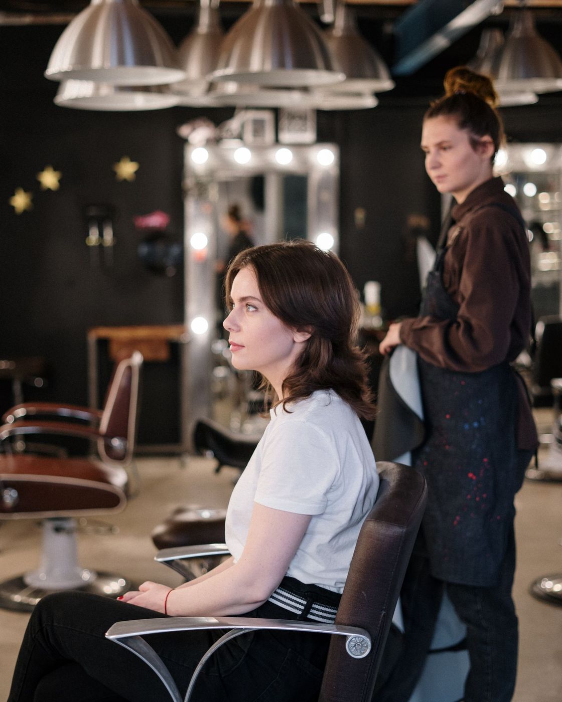 A client waits in the chair while a stylist prepares behind her