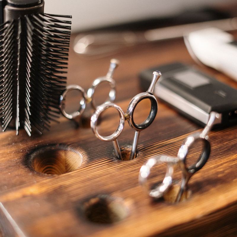 Round brushes and shears standing on a wooden station