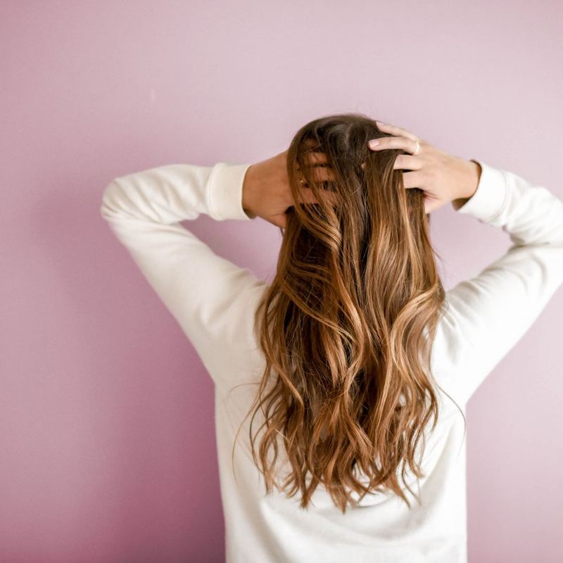 Long soft waves photographed from behind against a pink wall