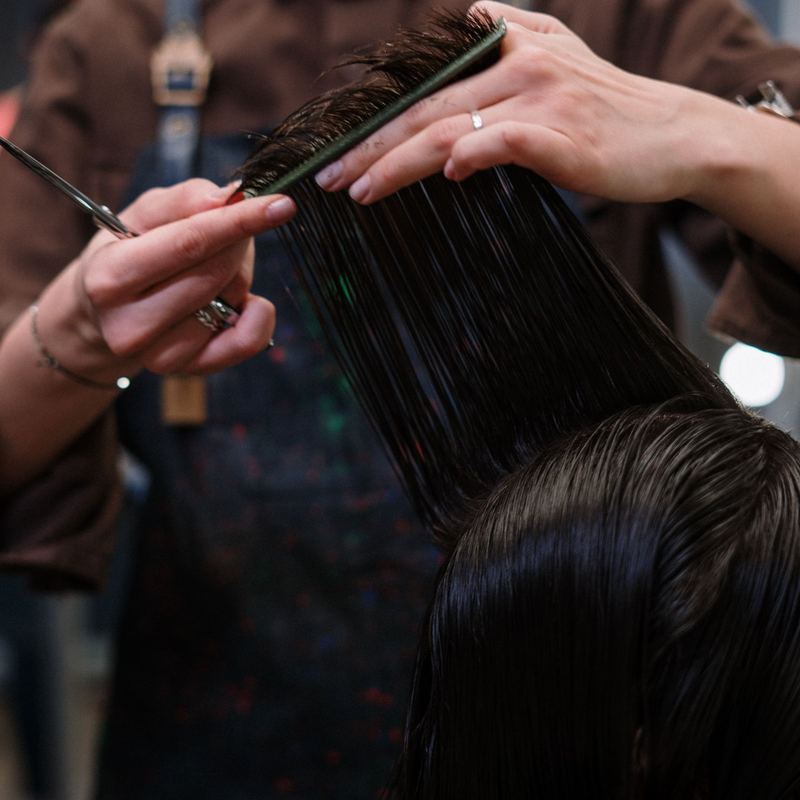 A comb lifts a section of wet hair mid-cut