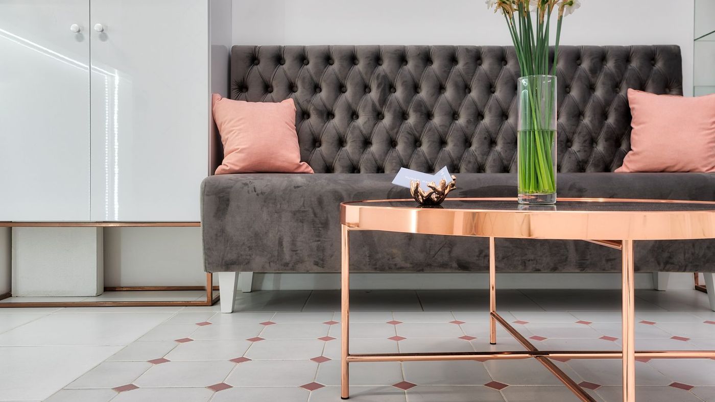 The grey velvet lounge sofa and copper table where clients wait