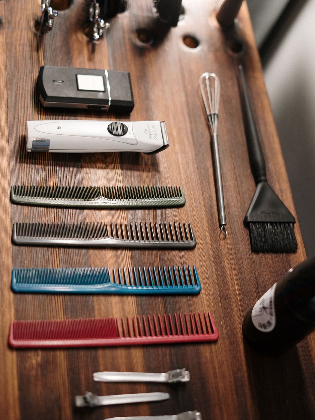 A row of combs and clippers laid out on a wooden styling station