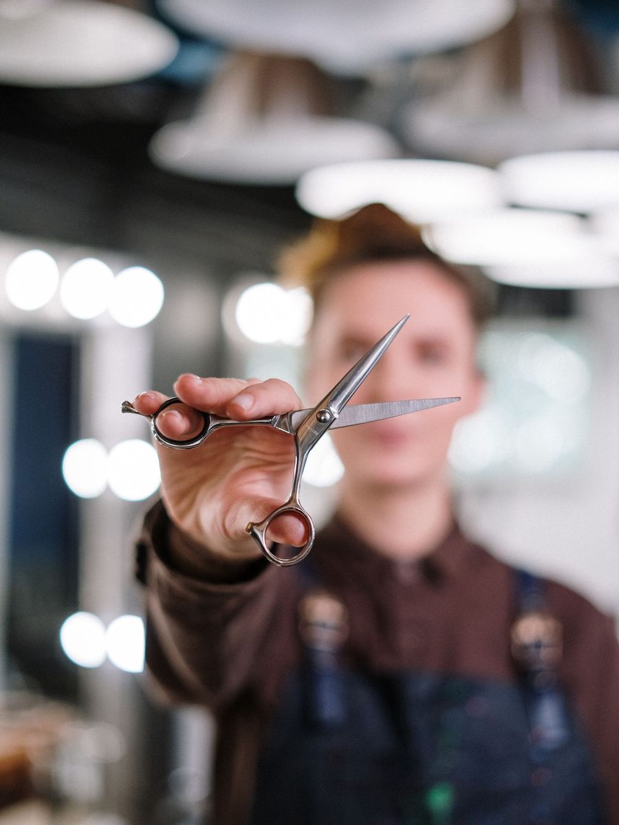 Iva holds a pair of scissors towards the camera in the atelier
