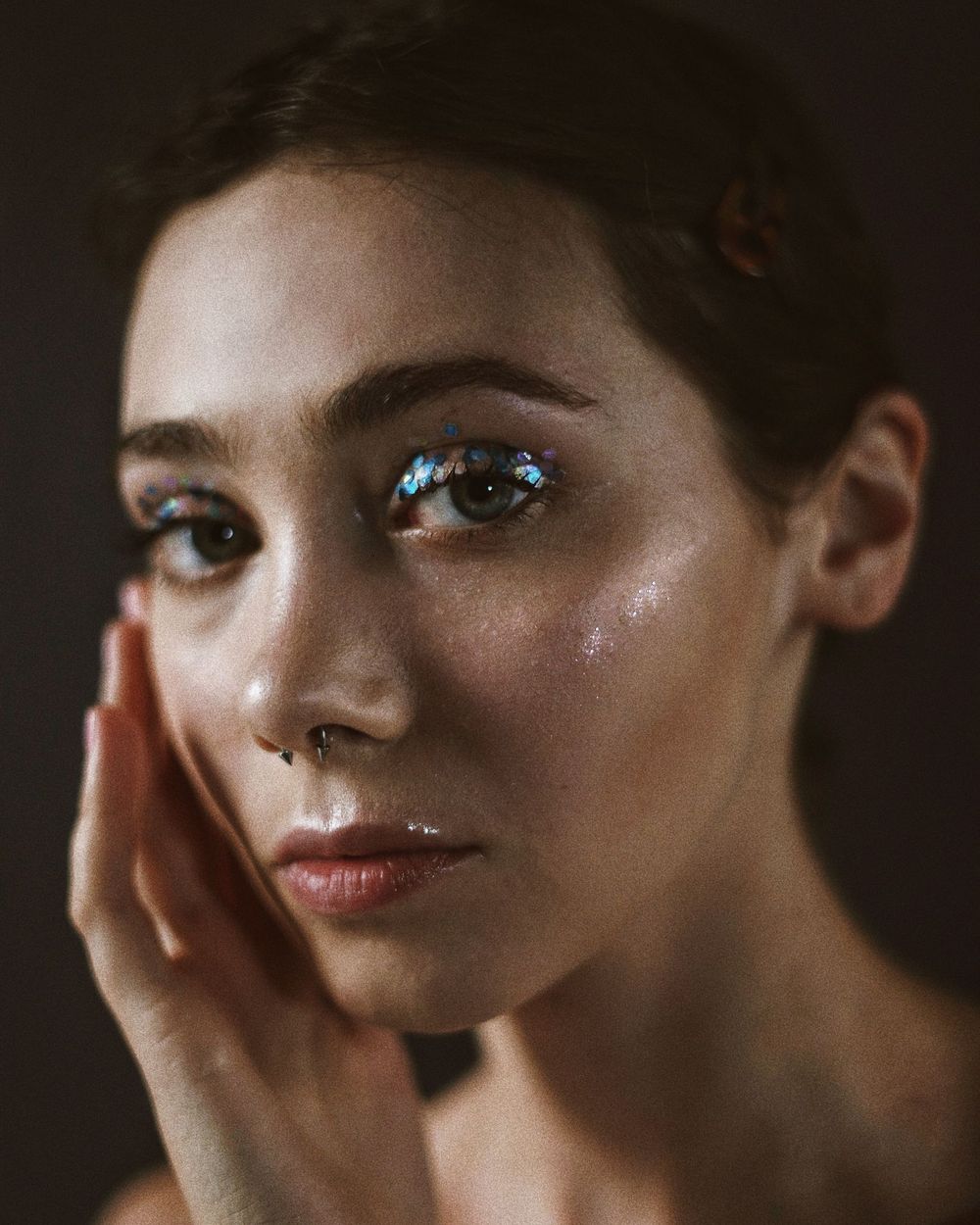 An editorial beauty look with glitter accents and a sleek crop