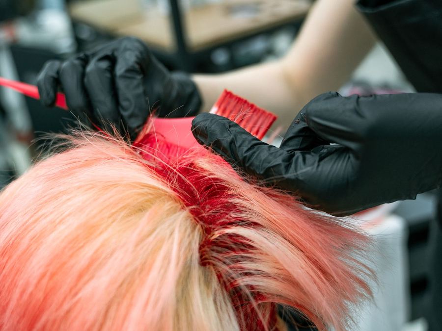 Colour being combed through sectioned hair with gloves