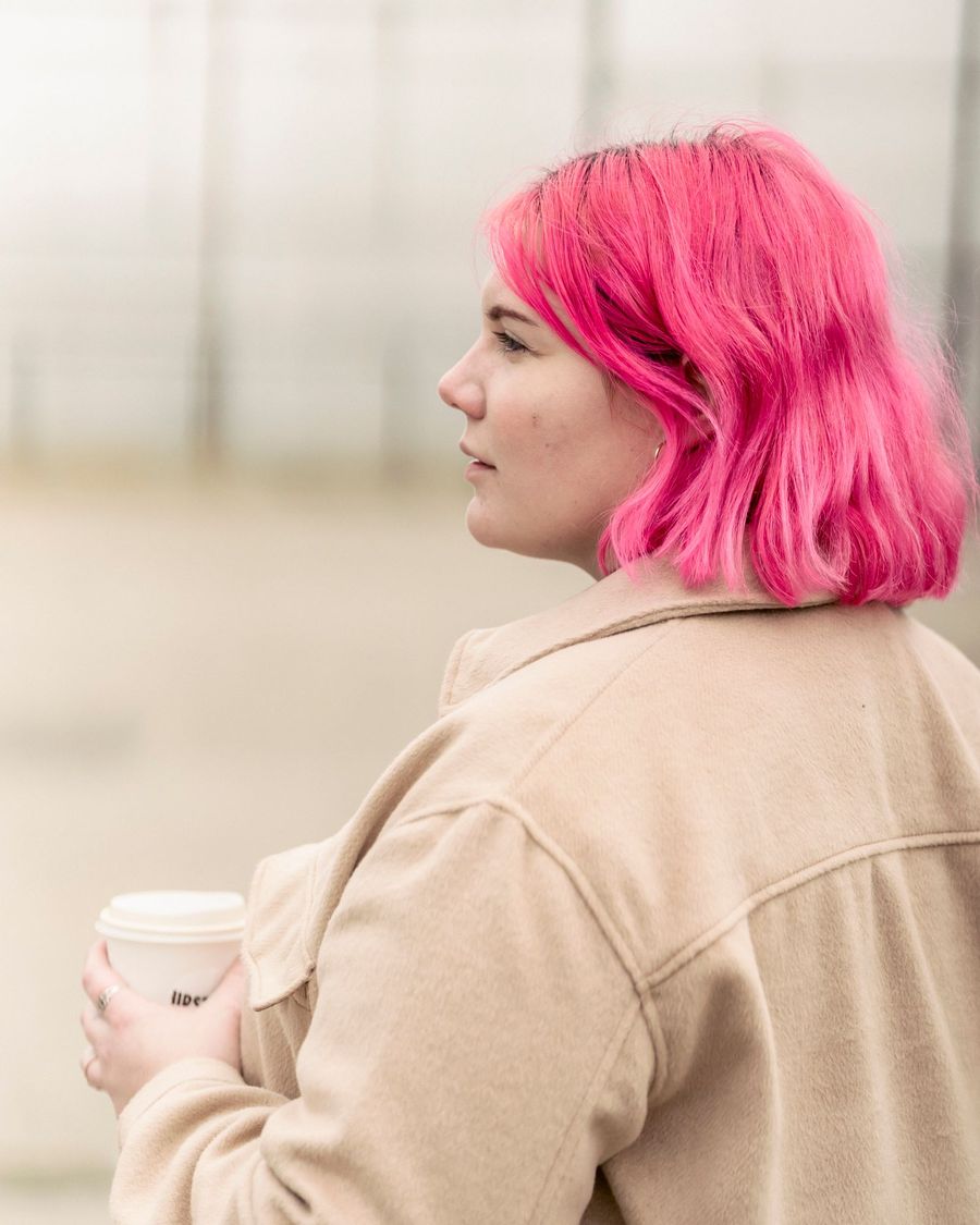 Vita with a bubblegum pink bob holding a coffee