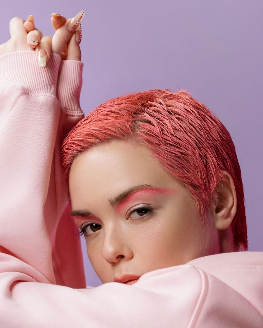 Rea with a coral pixie cut in studio light