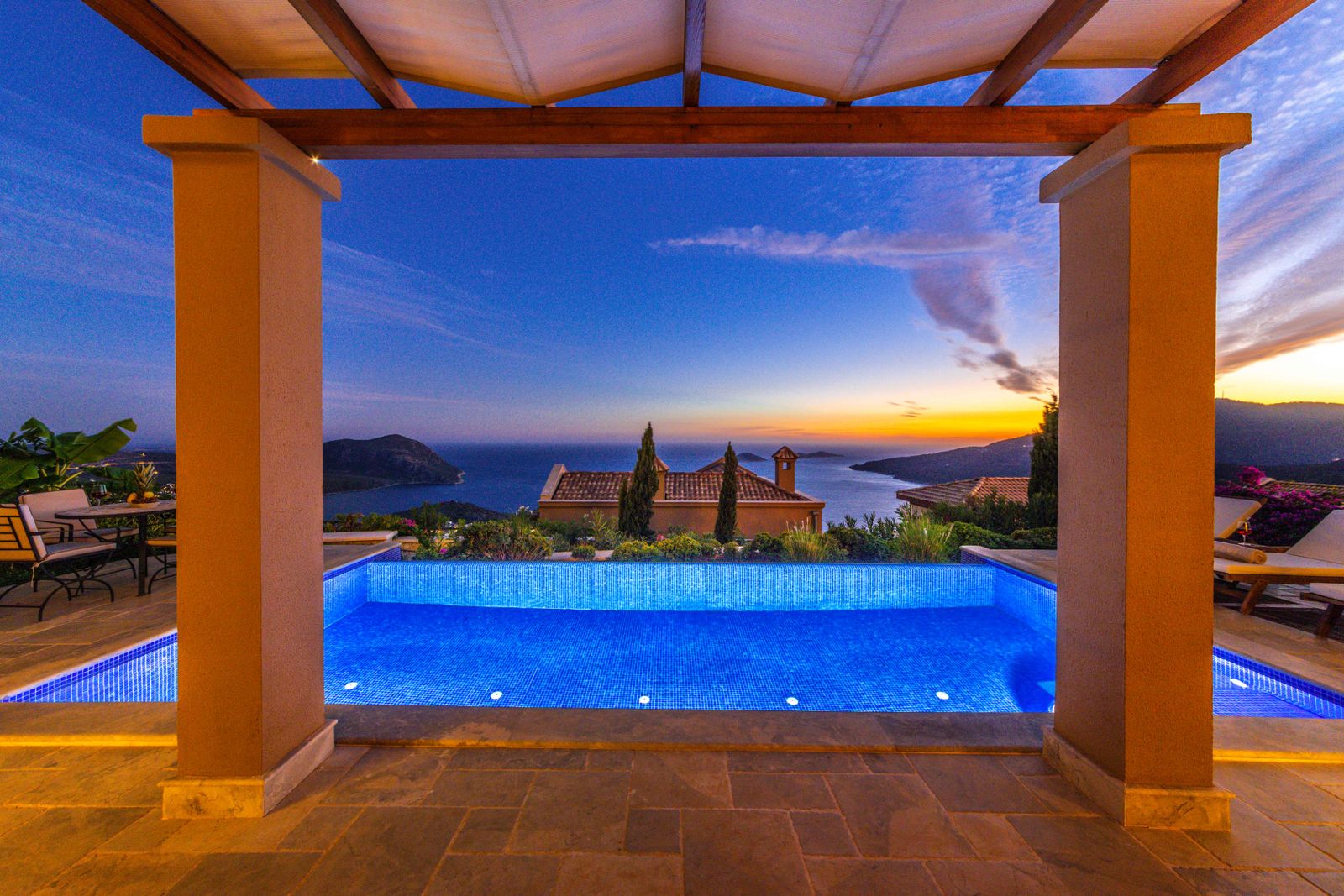 Stone terrace with a pergola overlooking the sea at dusk