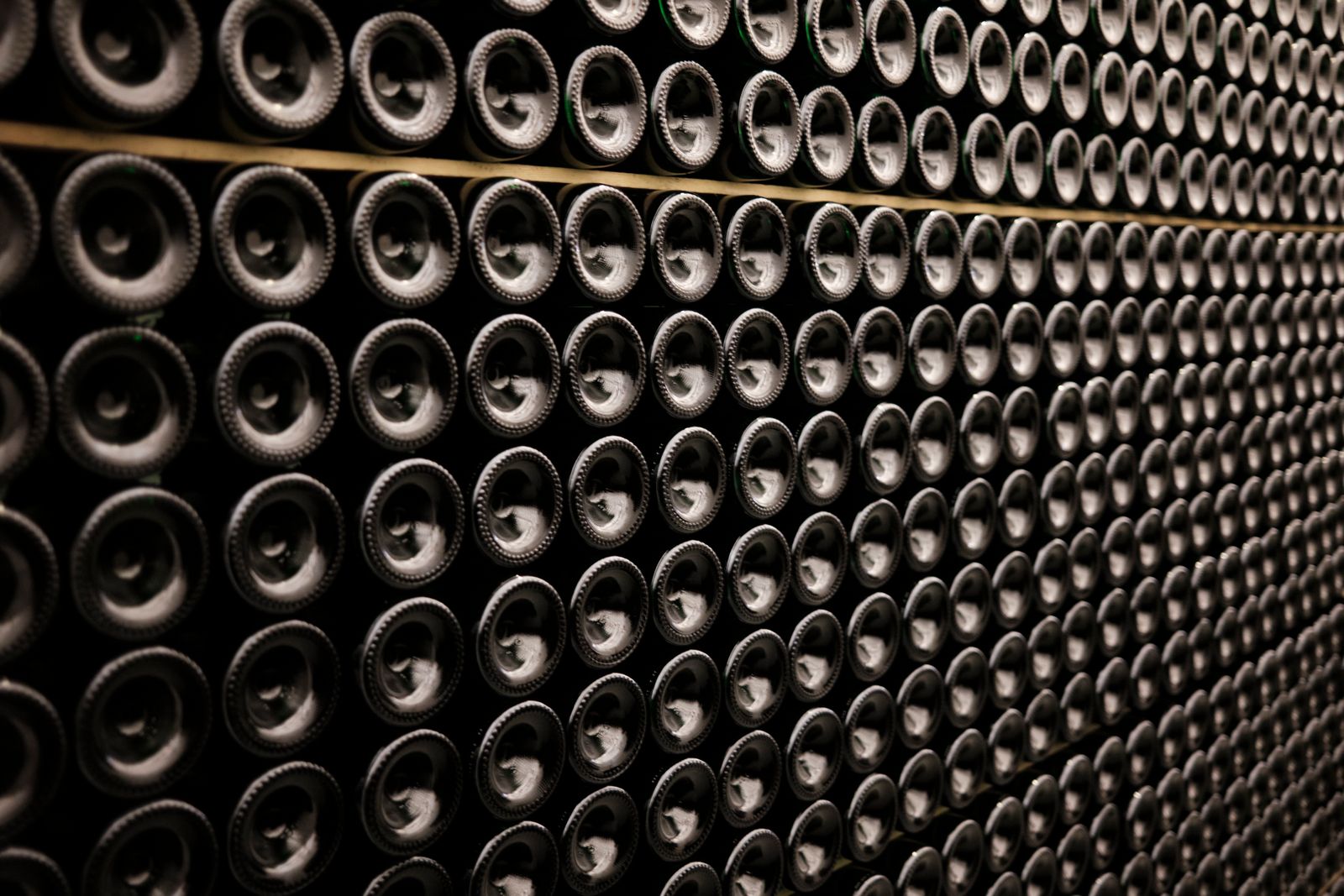 Ends of wine bottles resting in a honeycomb rack