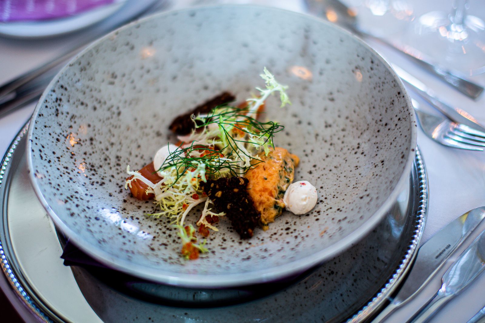 Dark ceramic plate with a composed vegetable course
