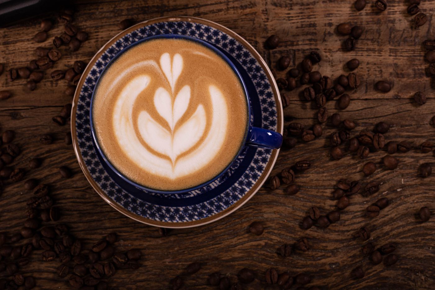 Cappuccino in an ornate blue cup on coffee beans