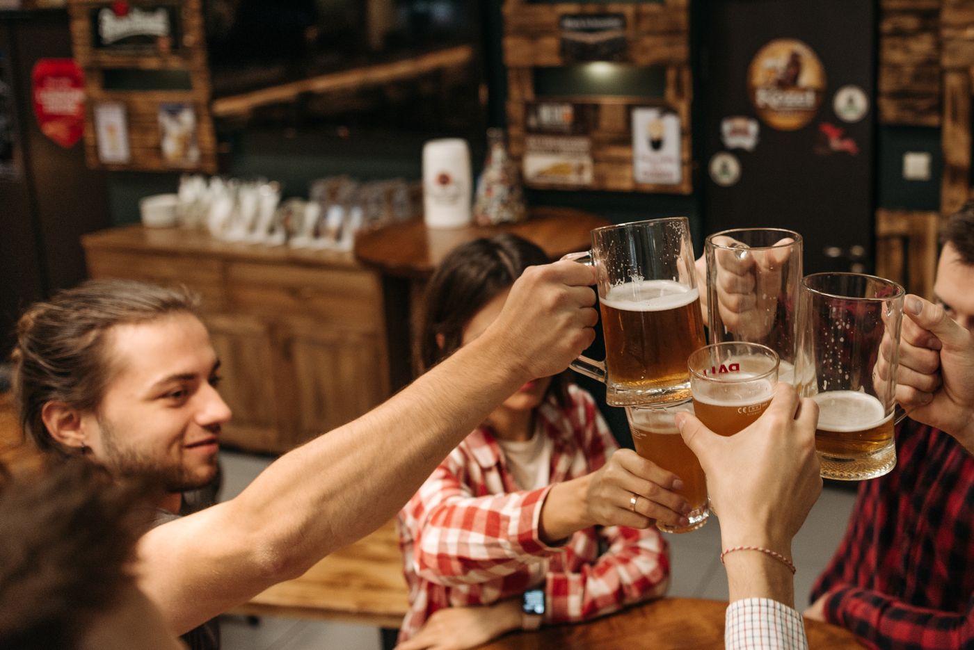 Friends raising beer glasses at a wooden table