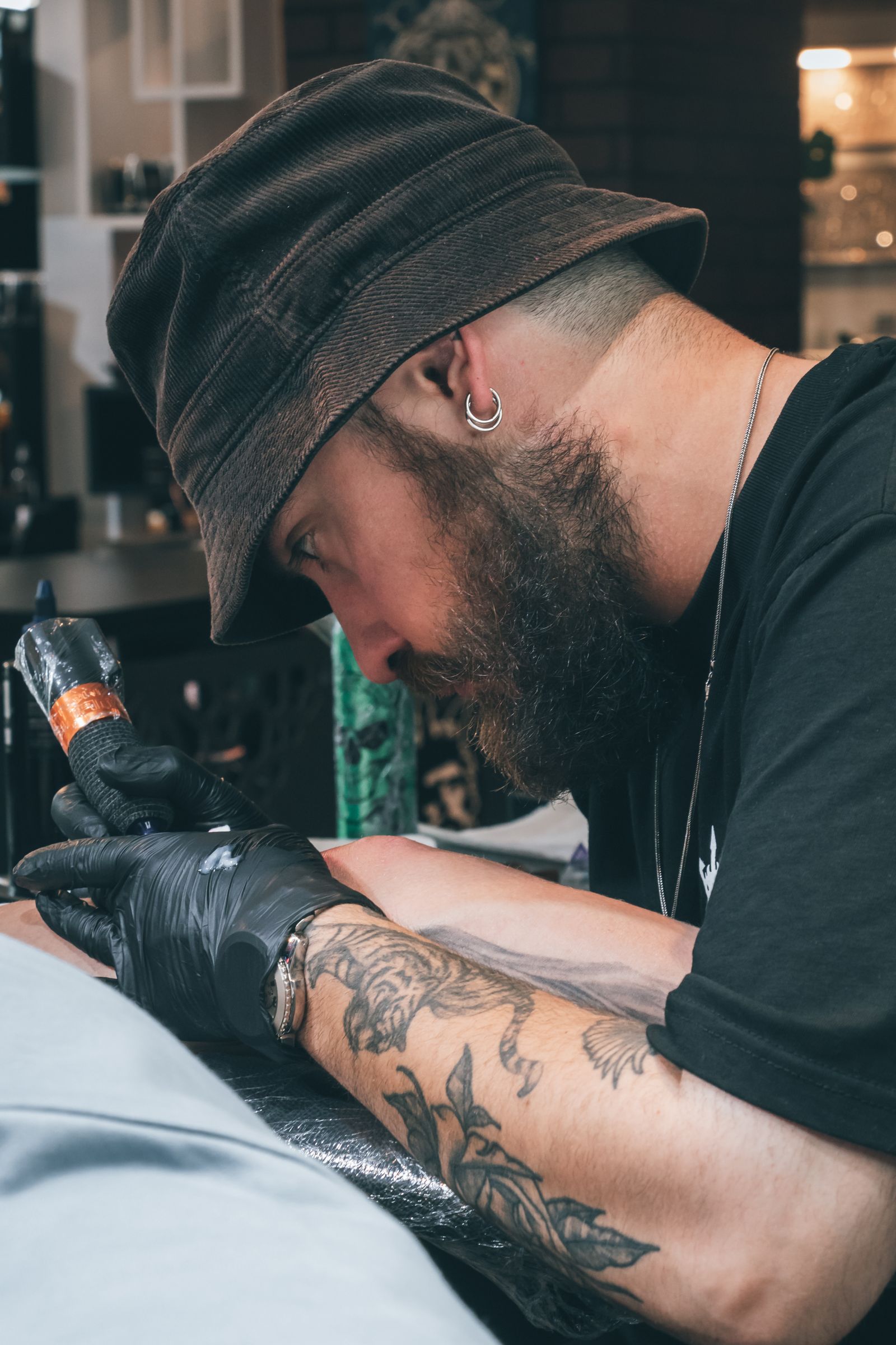 Resident artist leaning over a client mid-session in the Tinta studio