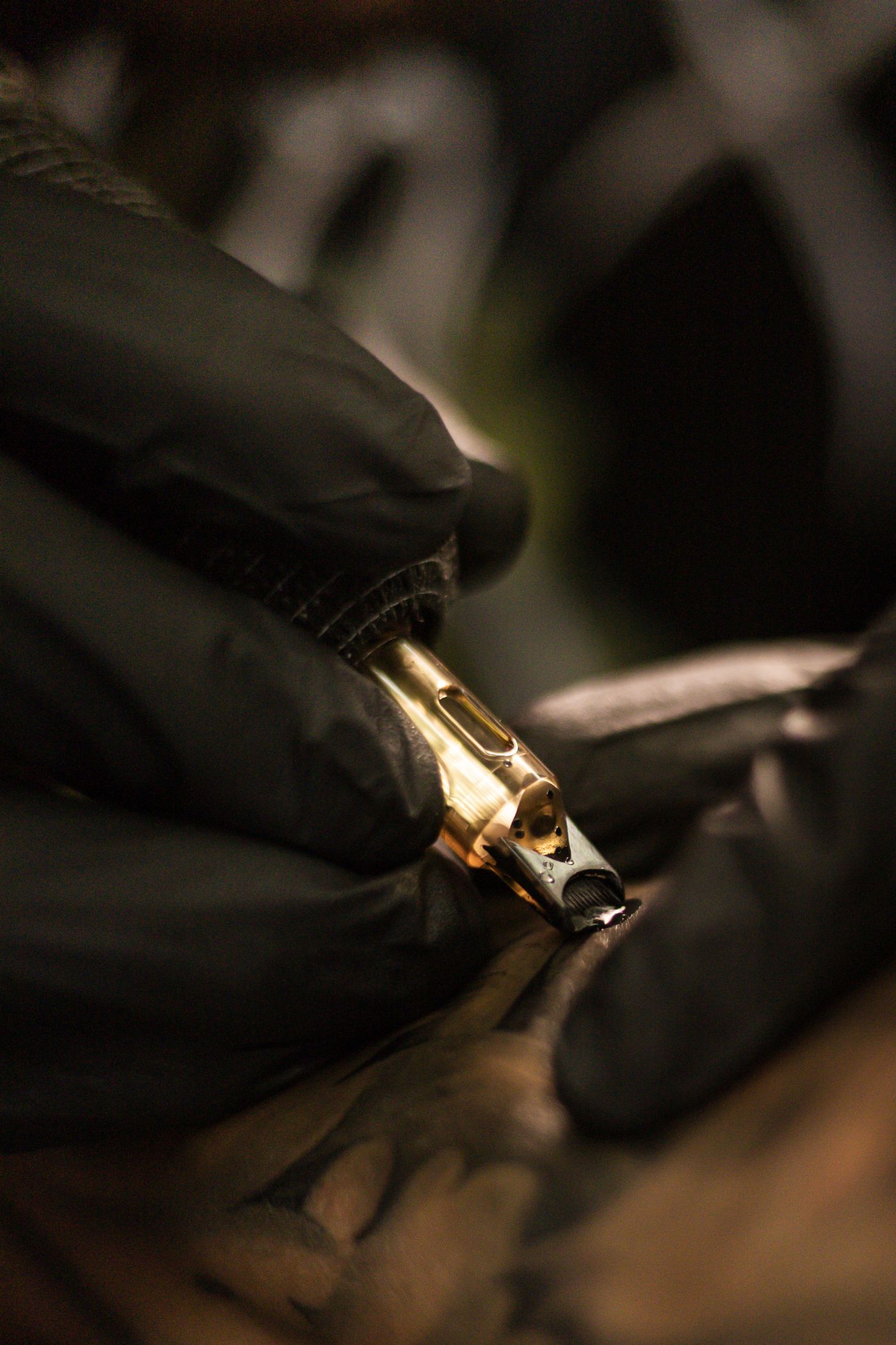 Macro of a tattoo machine mid-line, black gloves
